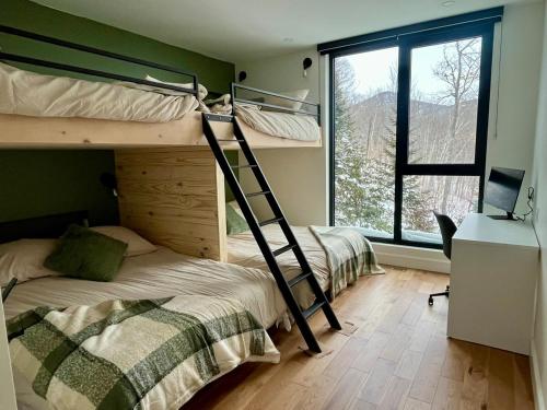 Dos literas en una habitación con ventana. en Le Föss, Fleuve, Sauna & Spa, en Petite-Rivière-Saint-François