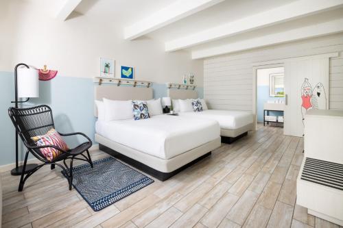 a white bedroom with a bed and a chair at Blue Flamingo Resort Key West in Key West