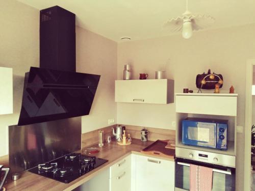 a kitchen with a stove and a microwave at Maison située aux confins de la Vallée du Loir in Le Lude