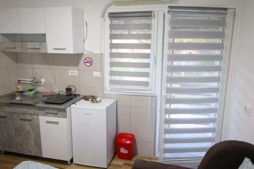 a kitchen with a window with white shutters on it at Banja Vrujci Apartmani Nikolic in Popadić