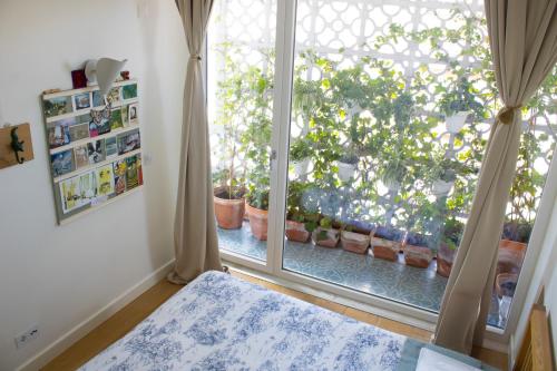 a bedroom with a window and a bed in front at Votre chambre avec salle de bain privée et balcon végétal à Lisbonne Amoreiras - Your Room with private bathroom and balcony in Lisbon Amoreiras in Lisbon