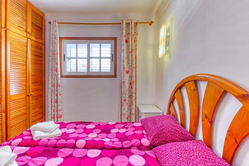 a bedroom with a bed with pink sheets and a window at Apartamento Roque Horizonte in Puerto Naos