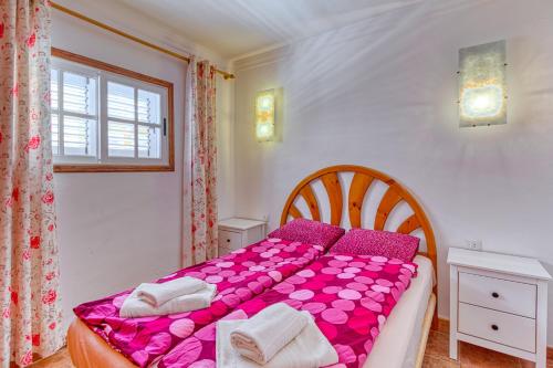 a bedroom with a bed with pink sheets and a window at Apartamento Roque Horizonte in Puerto Naos