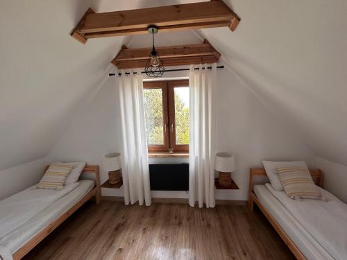 two beds in a room with a window at Leszczynowe Zacisze in Wiele