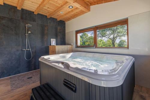 a large bath tub in a bathroom with a window at Au Soleil Couchant in Foncine-le-Haut