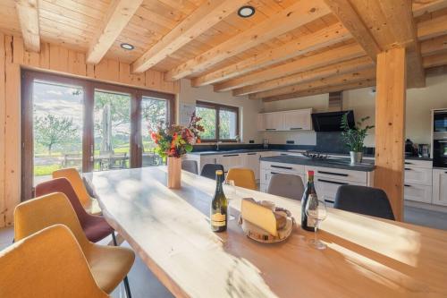 une cuisine avec une longue table en bois avec des bouteilles de vin dans l'établissement Au Soleil Couchant, à Foncine-le-Haut