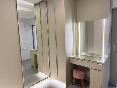 a dressing room with a mirror and a pink stool at Apartamento Central de Luxo- Ar condicionado, wi-fi in Patos de Minas