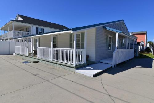 a house with a porch and a white fence at Suns Out Steps to Beach w Private Pool in Cherry Grove in Myrtle Beach