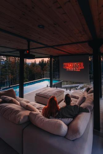 a couple sitting on a couch in front of a pool at Montagne le Maelström in Lac-Beauport