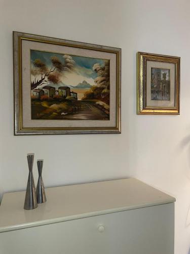 a painting on a white wall with vases on a shelf at Casa vacanza PASsaggio in Como