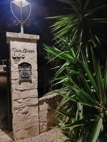 a stone sign for a restaurant with a palm plant at Villa don peppe in Selva di Fasano