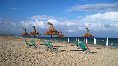 a group of chairs and umbrellas on a beach at Hotel Ristorante Antica Marina in Nicotera Marina