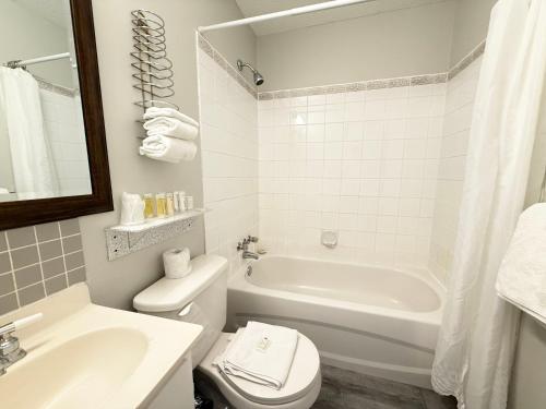 a bathroom with a white tub and a toilet and a sink at Departure Bay Motel in Nanaimo