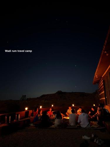 a group of people sitting around a table under the night sky at Wadi Rum Travel camp in Wadi Rum
