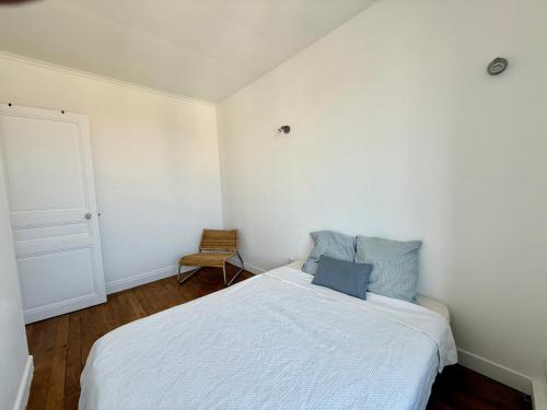 une chambre avec un lit blanc et une chaise dans l'établissement Charmant appartement proche Paris, à Villeneuve-Saint-Georges