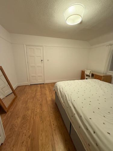 a bedroom with a bed and a wooden floor at Ibrahim's House in Chigwell