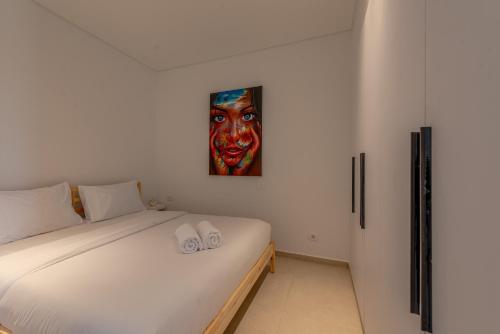 a bedroom with a bed with a painting on the wall at Chic 1 BR with private jacuzzi in Banī Ghālib