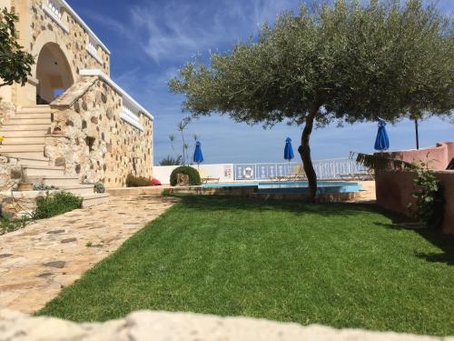 a yard with a tree and a swimming pool at Ilios Village in Stalos