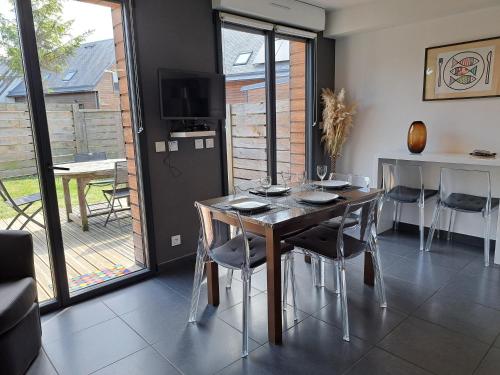 une salle à manger avec une table, des chaises et une télévision dans l'établissement Villa Marylou, à Bernières-sur-Mer
