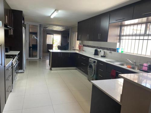 a large kitchen with black cabinets and white tile floors at Ludiz guest house in Parow