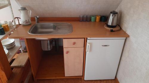 イェトジホヴィツェにあるApartmán Roubenka Všemilyのシンクと冷蔵庫のある小さなキッチン