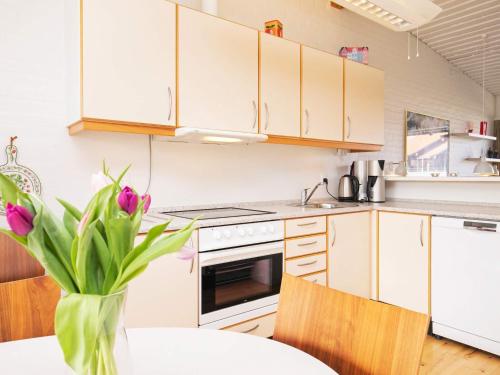 a kitchen with white cabinets and a table with a vase of flowers at 6 person holiday home on a holiday park in Sæby in Sæby