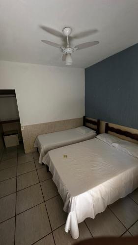 two beds in a room with a ceiling fan at Casa do Mar Inn Paraty in Paraty