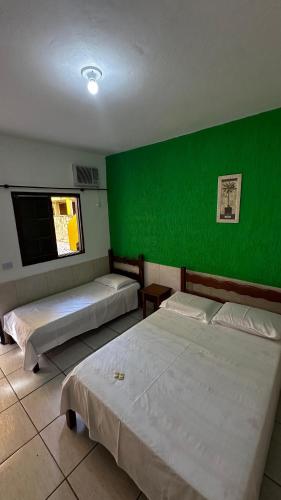 two beds in a room with a green wall at Casa do Mar Inn Paraty in Paraty