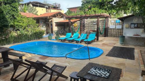 a swimming pool with blue chairs and a table at Pousada Casa Do Angelo in Jericoacoara