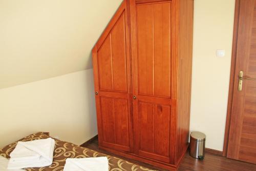 a bedroom with a wooden cabinet next to a bed at Willa Ostoja in Świeradów-Zdrój