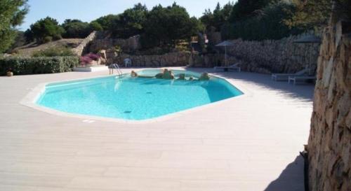 a large swimming pool with three people in it at Casa Alessandra, Apartment in Porto Cervo in Porto Cervo
