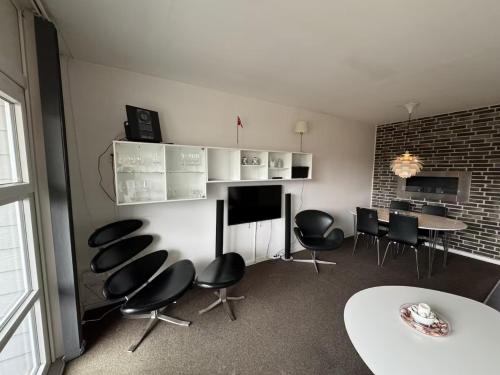 a room with chairs and a table and a table and a wall at 4 Personer Ferielejlighed - Henne Strand in Henne Strand