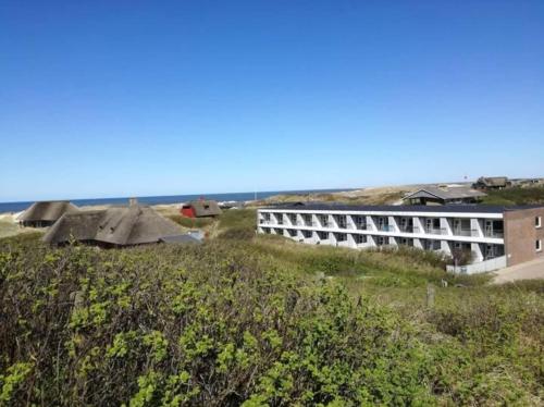 a building on top of a hill next to the ocean at 4 Personer Ferielejlighed - Henne Strand in Henne Strand