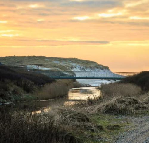 a bridge over a body of water at sunset at 4 Personer Ferielejlighed - Henne Strand in Henne Strand