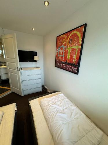 a bedroom with a bed and a painting on the wall at 4 Personer Ferielejlighed - Henne Strand in Henne Strand