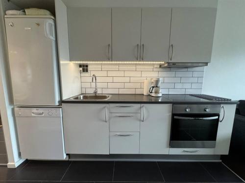 a white kitchen with a sink and a refrigerator at 4 Personer Ferielejlighed - Henne Strand in Henne Strand