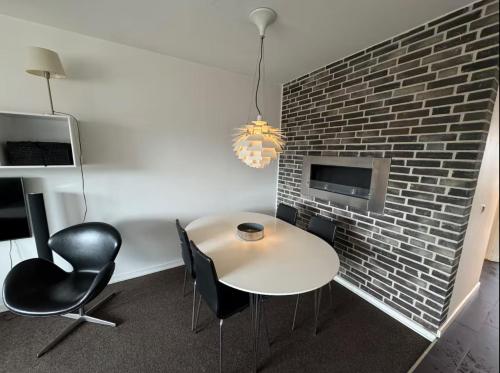 a room with a table and chairs and a brick wall at 4 Personer Ferielejlighed - Henne Strand in Henne Strand