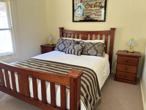 - une chambre avec un lit en bois et 2 tables de chevet dans l'établissement School Cottage, à Walhalla