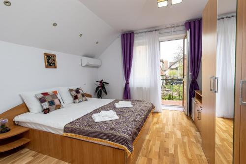 a bedroom with a large bed with purple curtains at Green House Arini in Sibiu