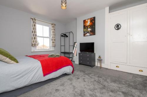 1 dormitorio con 1 cama con manta roja y TV en The Harwich Hideaway, en Harwich