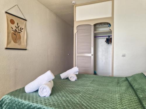 a bedroom with a green bed with towels on it at Appartement terrasse vue mer et piscine in Le Diamant