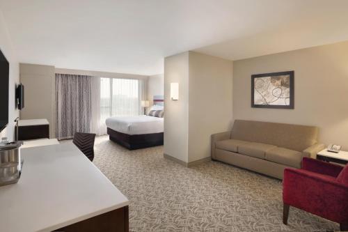 Holiday Inn Chicago Schaumburg, an IHG Hotel في شامبورغ: غرفة في الفندق مع أريكة وسرير