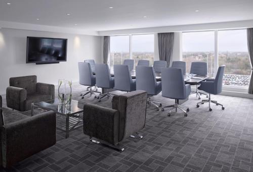 a conference room with a table and chairs and a tv at Radisson Blu Manchester Airport in Hale