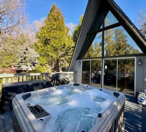 a hot tub on a deck with a house at Hot Tub-EV-AC-Kid Friendly-Arcade Game-Lake Access in Lake Arrowhead