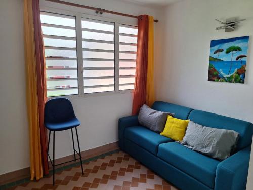 a living room with a blue couch and a window at TI-KAZ fleurie, l'escapade bouillonaise in LʼAjoupa-Bouillon