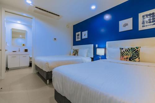 a bedroom with two beds and a blue wall at Azure Beach Residences in Palm-Eagle Beach