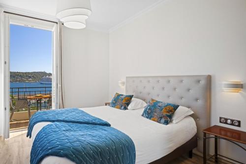 a bedroom with a bed with a large window at Hotel De La Darse in Villefranche-sur-Mer