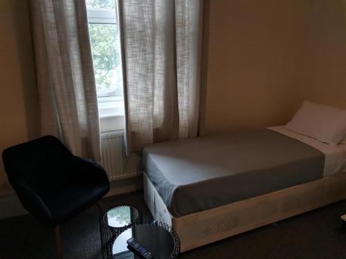 a bedroom with a bed and a chair and a window at Ax 1 Bed and Breakfast in London
