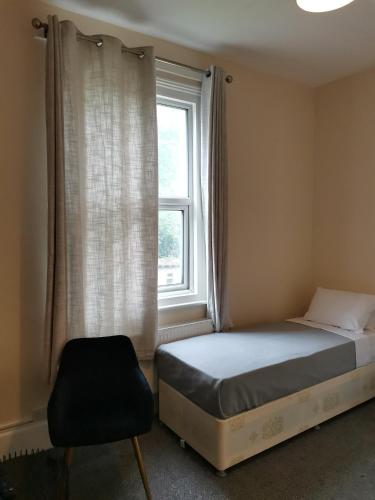 a bedroom with a bed and a window and a chair at Ax 1 Bed and Breakfast in London