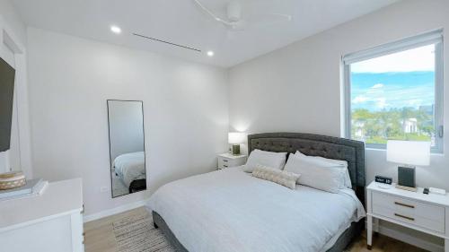 a white bedroom with a bed and a large window at Modern Luxury 2bed by 7 Mile Beach in Upper Land